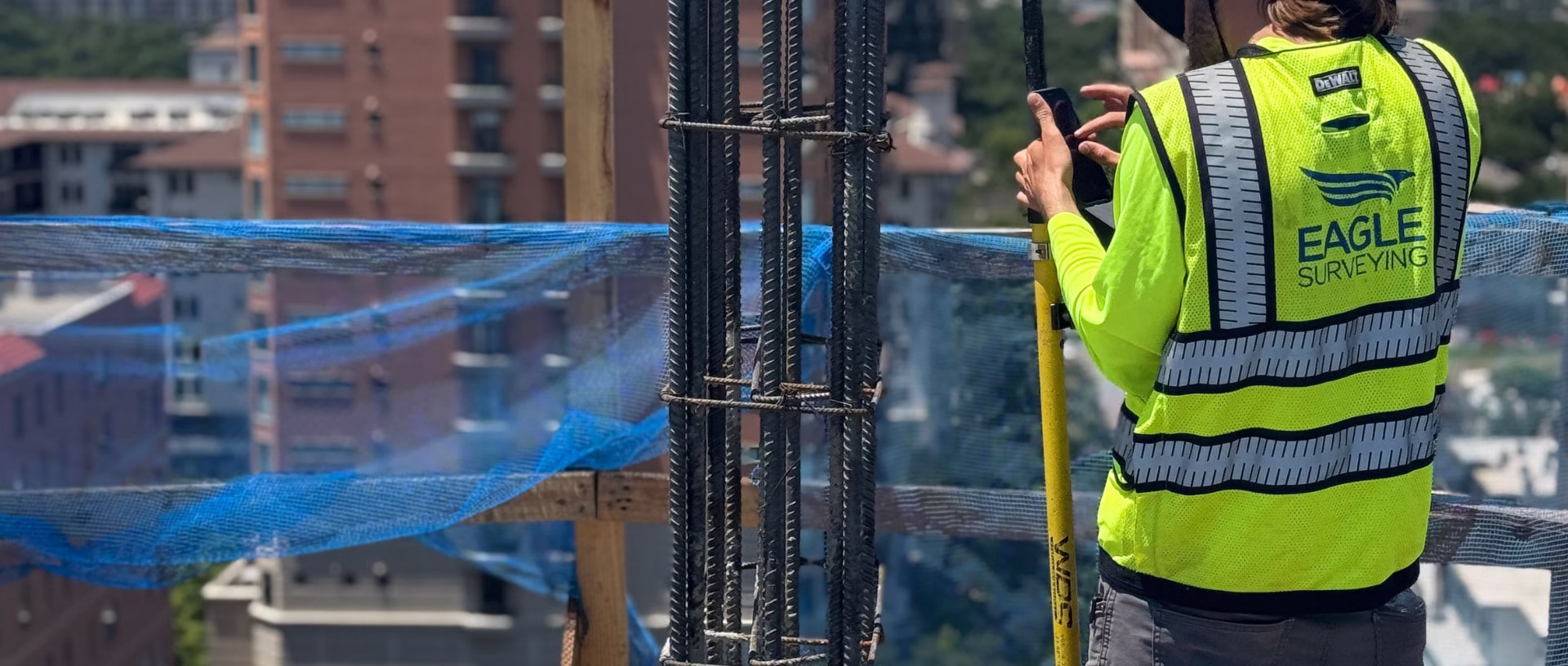 Surveyor in a yellow vest on a high-rise jobsite